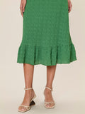 Green ruffled skirt worn by a person on a beige background