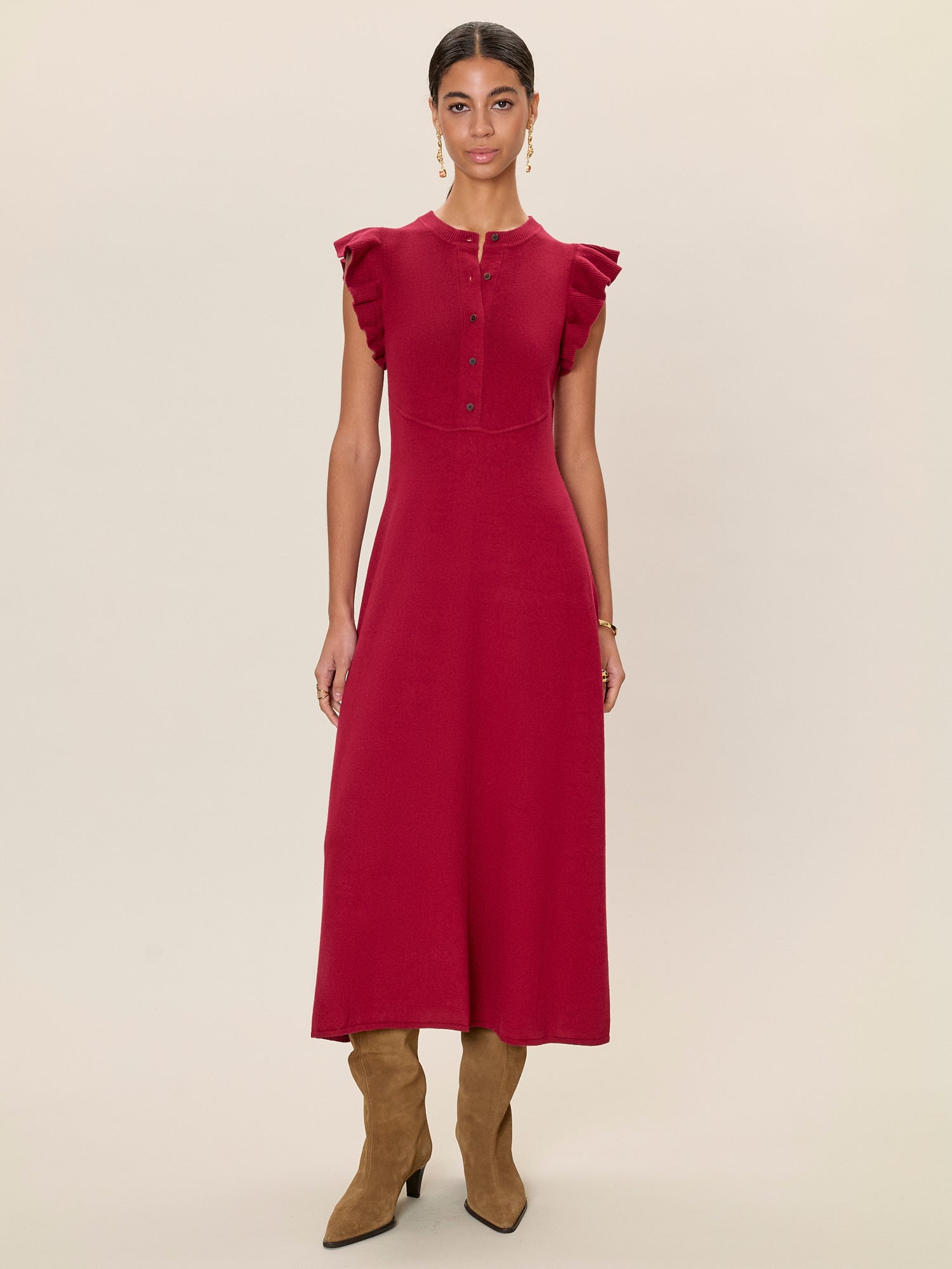 Woman wearing a red dress with ruffled sleeves on a beige background