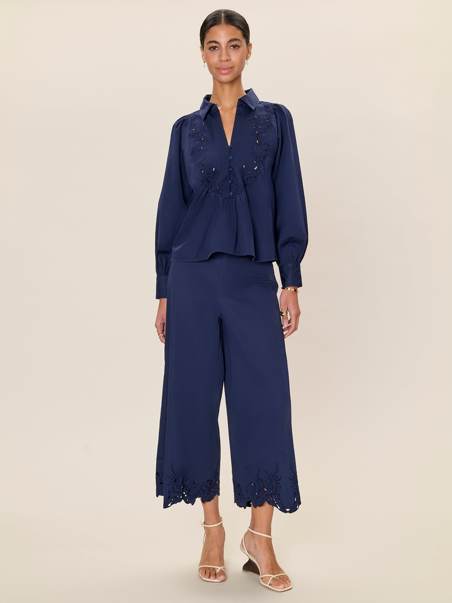 Woman wearing a navy blue outfit with a matching top and pants on a beige background