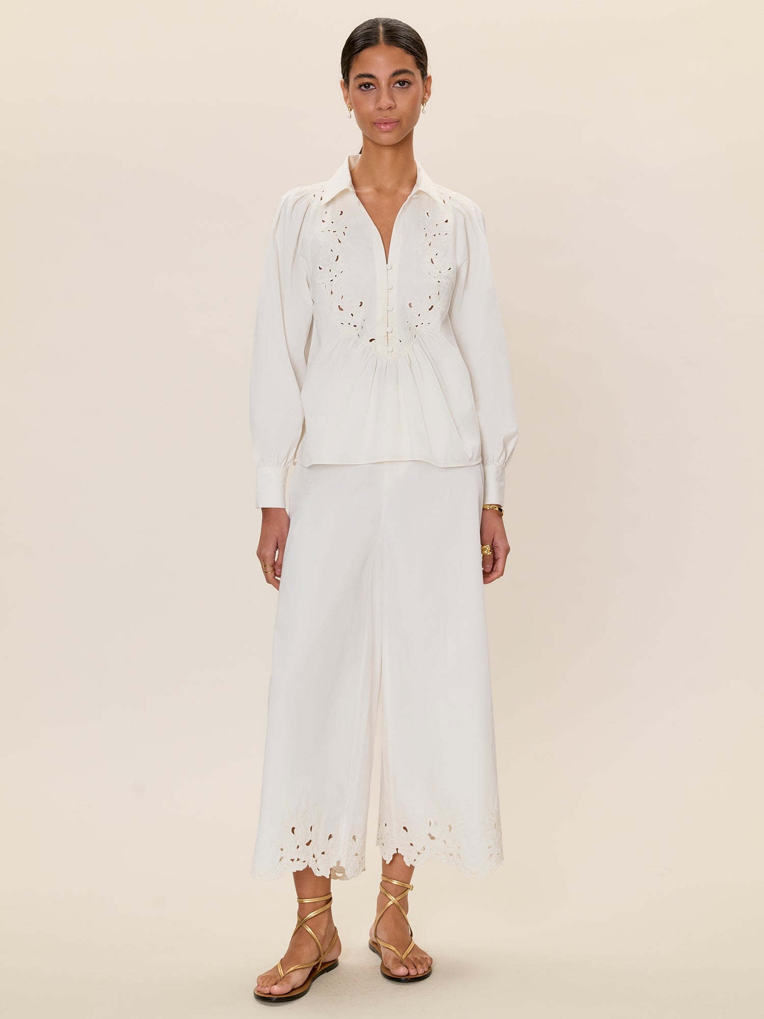 Woman wearing a white outfit with embroidered details on a beige background