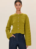 Woman wearing a green knitted cardigan against a beige background